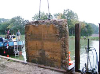 ein Schwimmbagger hebt ein Betonteil aus dem Wasser